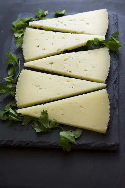 Muitas fatias de queijo com salsa em uma ardósia de pedra — Fotografia de Stock