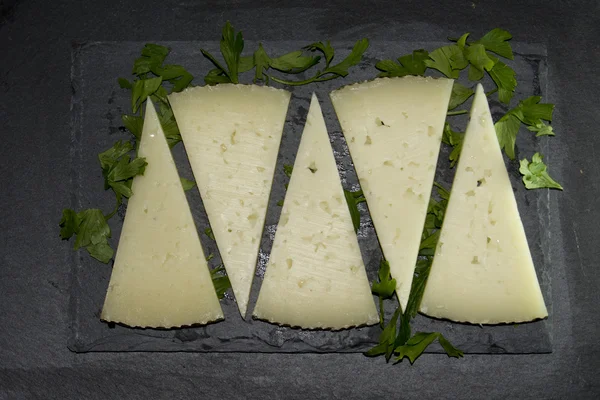 Muitas fatias de queijo com salsa em uma ardósia de pedra — Fotografia de Stock