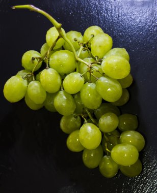 Siyah bir kayrak taş üzerinde üzüm demet