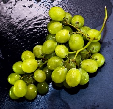 Siyah bir kayrak taş üzerinde üzüm demet