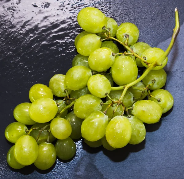 Ramo de uvas en una piedra de pizarra negra — Foto de Stock