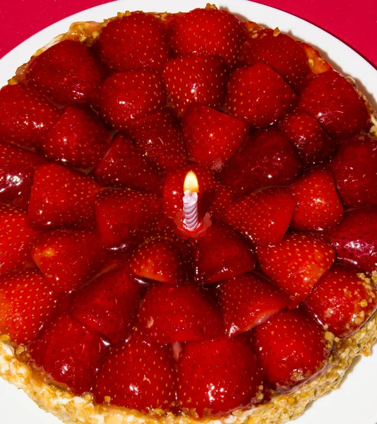 Jahodový dort, mandlemi a smetanou se svíčkou na červené pozadí — Stock fotografie