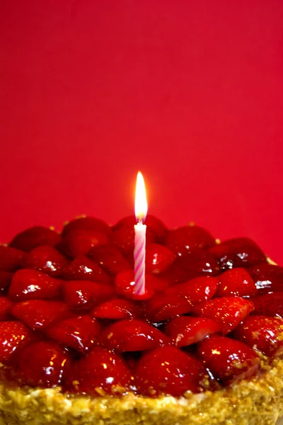 Jahodový dort, mandlemi a smetanou se svíčkou na červené pozadí — Stock fotografie