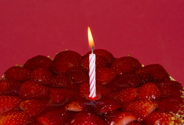 Клубничный торт, миндаль и сливки со свечой на красном бэкгре — стоковое фото