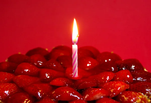 Torta di fragole, mandorle e panna con candela su dorso rosso — Foto Stock