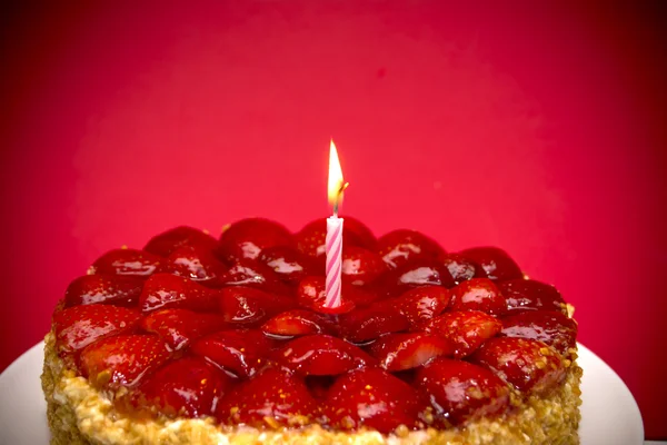 Клубничный торт, миндаль и сливки со свечой на красном бэкгре — стоковое фото