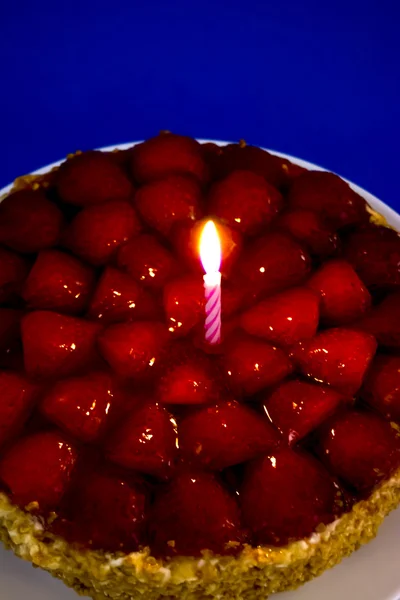 Jahodový dort, mandlemi a smetanou se svíčkou na modrém pozadí — Stock fotografie