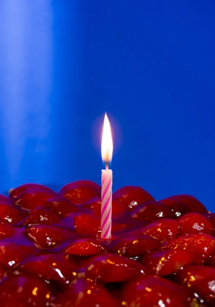 Tarta de fresa, almendras y crema con una vela en un respaldo azul —  Fotos de Stock