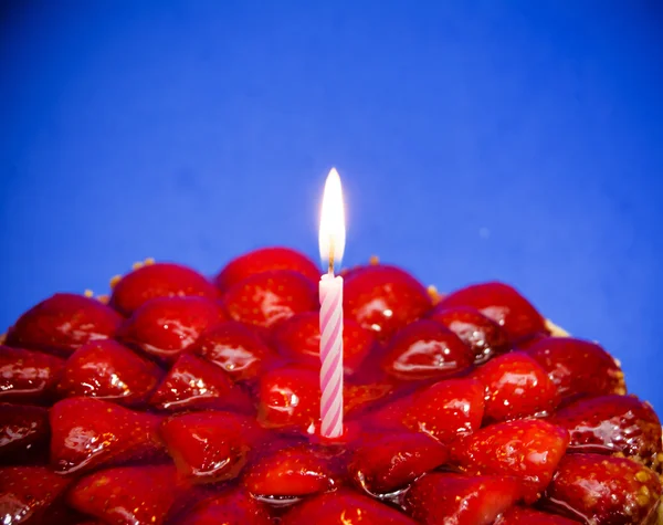 Gâteau aux fraises, amandes et crème avec une bougie sur un fond bleu — Photo