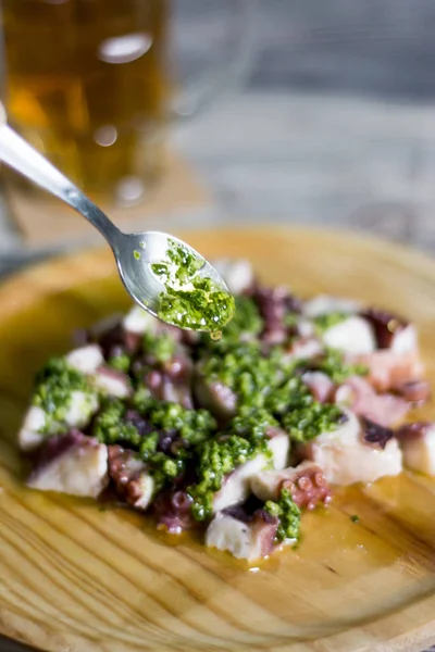 Putting sauce with a teaspoon to a plate of octopus with paprika — Stock Photo, Image