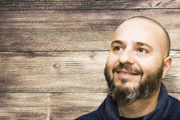 Bello, calvo uomo con la barba su uno sfondo di legno — Foto Stock