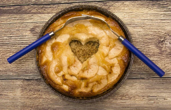 Torta di mele a forma di cuore cavo e due forchette intrecciate su un — Foto Stock