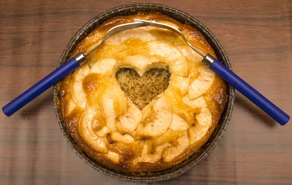 Torta di mele a forma di cuore cavo e due forchette intrecciate su un — Foto Stock