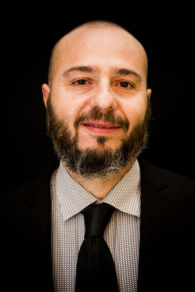 Handsome, bald man with beard,  in suit and tie, on black backgr