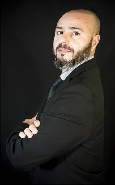 Hombre guapo, calvo con barba, en traje y corbata, sobre fondo negro —  Fotos de Stock