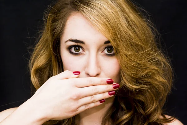 Beautiful woman covering her mouth with her hand over black Back — Stock Photo, Image