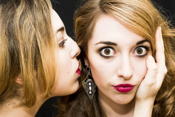 Two beautiful women where one of them is telling a secret to the — Stock Photo, Image