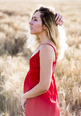Kırmızı elbiseli, günbatımı buğday sahasının güzel sarışın kadın