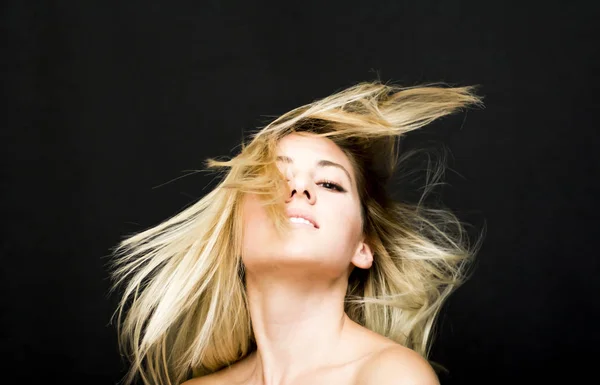 Porträtt av en vacker kvinna som skakar hennes hår på svart backgrou — Stockfoto