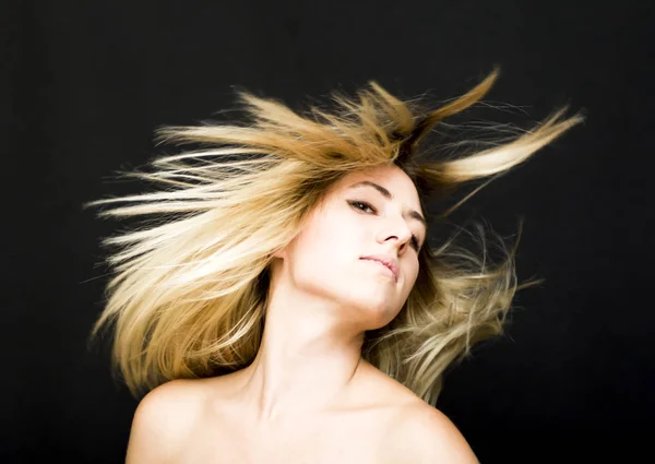 Portrait of a beautiful woman shaking her hair on black backgrou — Stock Photo, Image