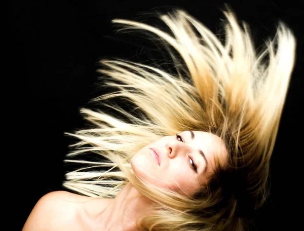 Retrato de una hermosa mujer sacudiendo su cabello en el backgrou negro — Foto de Stock