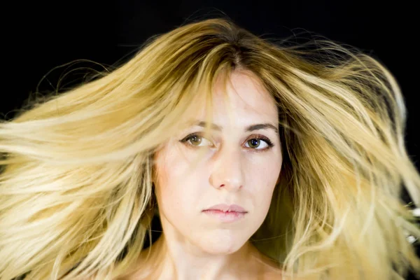 Portrait of a beautiful woman shaking her hair on black backgrou — Stock Photo, Image