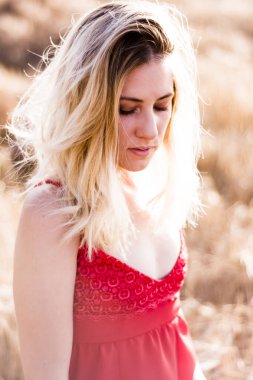 Kırmızı elbiseli, günbatımı buğday sahasının güzel sarışın kadın