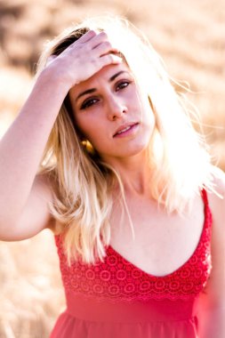 Kırmızı elbiseli, günbatımı buğday sahasının güzel sarışın kadın