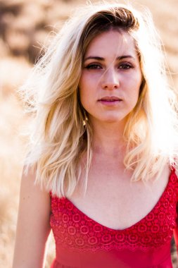 Kırmızı elbiseli, günbatımı buğday sahasının güzel sarışın kadın