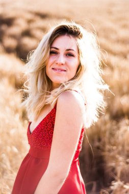 Kırmızı elbiseli, günbatımı buğday sahasının güzel sarışın kadın