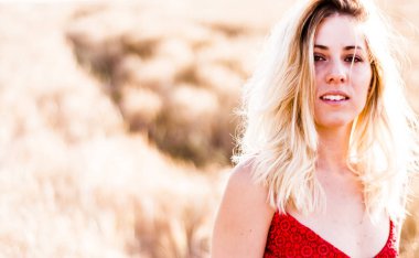 Kırmızı elbiseli, günbatımı buğday sahasının güzel sarışın kadın