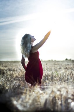 Arkadan aydınlatmalı dikey bir w üzerinde kırmızı bir elbise içinde güzel sarışın kadın