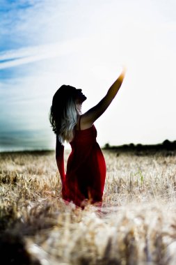 Arkadan aydınlatmalı dikey bir w üzerinde kırmızı bir elbise içinde güzel sarışın kadın