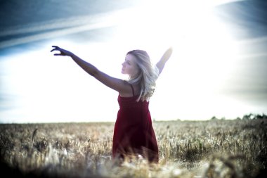 Arkadan aydınlatmalı dikey bir w üzerinde kırmızı bir elbise içinde güzel sarışın kadın