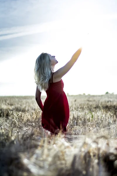 Rétro-éclairé portrait de belle femme blonde dans une robe rouge, sur un w — Photo