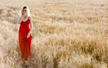 Kırmızı elbiseli, günbatımı buğday sahasının güzel sarışın kadın