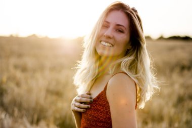 Kırmızı elbiseli, günbatımı buğday sahasının güzel sarışın kadın