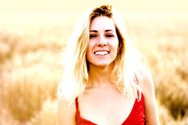 Hermosa mujer rubia en un vestido rojo, en un campo de trigo al atardecer —  Fotos de Stock