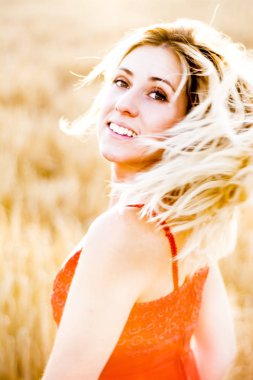 Kırmızı elbiseli, günbatımı buğday sahasının güzel sarışın kadın