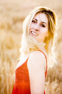 Kırmızı elbiseli, günbatımı buğday sahasının güzel sarışın kadın