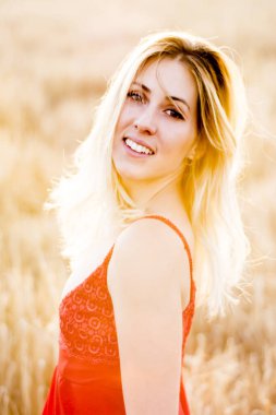 Kırmızı elbiseli, günbatımı buğday sahasının güzel sarışın kadın