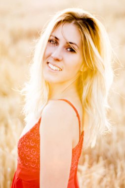 Kırmızı elbiseli, günbatımı buğday sahasının güzel sarışın kadın