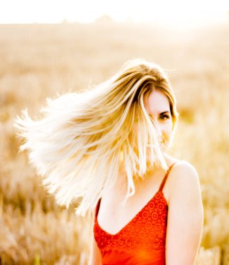 Kırmızı elbiseli, günbatımı buğday sahasının güzel sarışın kadın