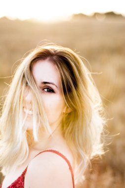 Kırmızı elbiseli, günbatımı buğday sahasının güzel sarışın kadın