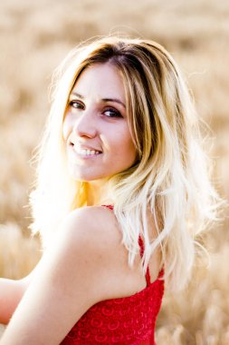 Kırmızı elbiseli, günbatımı buğday sahasının güzel sarışın kadın
