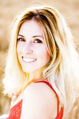 Kırmızı elbiseli, günbatımı buğday sahasının güzel sarışın kadın