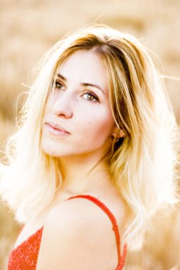 Kırmızı elbiseli, günbatımı buğday sahasının güzel sarışın kadın