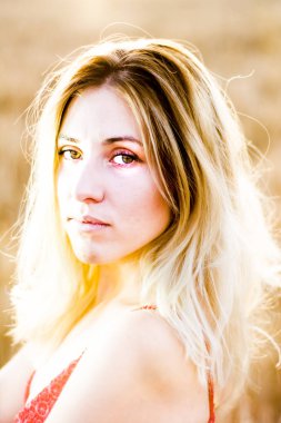 Kırmızı elbiseli, günbatımı buğday sahasının güzel sarışın kadın