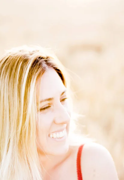 Belle femme blonde en robe rouge, sur un champ de blé au coucher du soleil — Photo