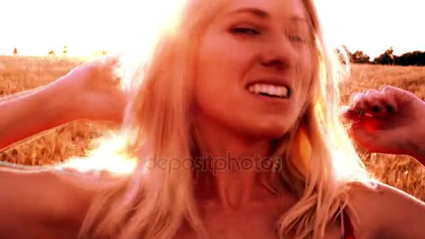 Красивая блондинка в красном платье, на пшеничном поле на закате — стоковое видео